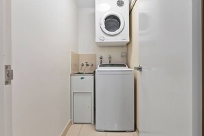 A compact laundry room with a washing machine, a dryer, and a small sink. - Poolside Paradise Cairns - 9 Pools BBQ Gym (Westcourt)