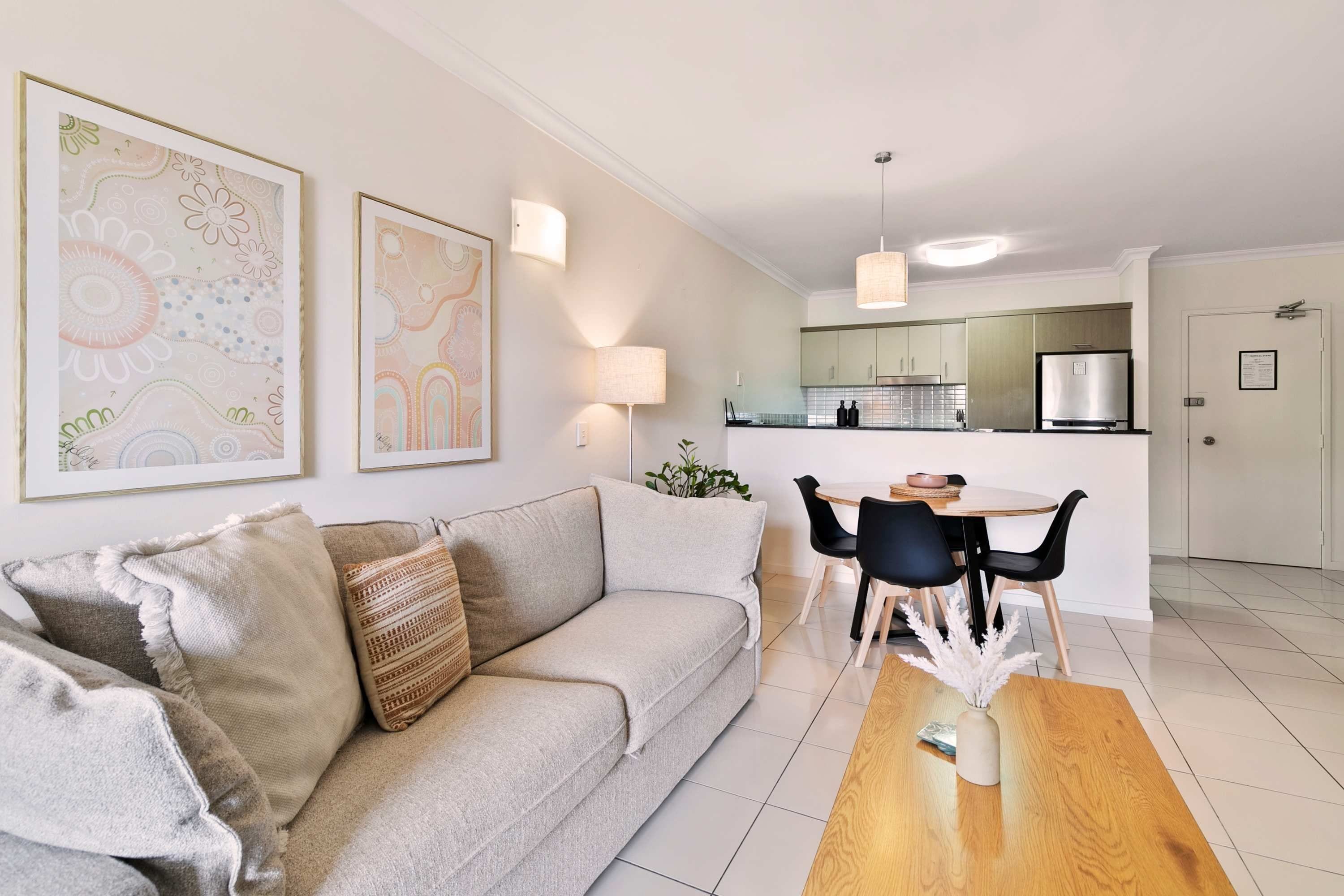 A modern living room with a sofa, a dining table, and a kitchen in the background.