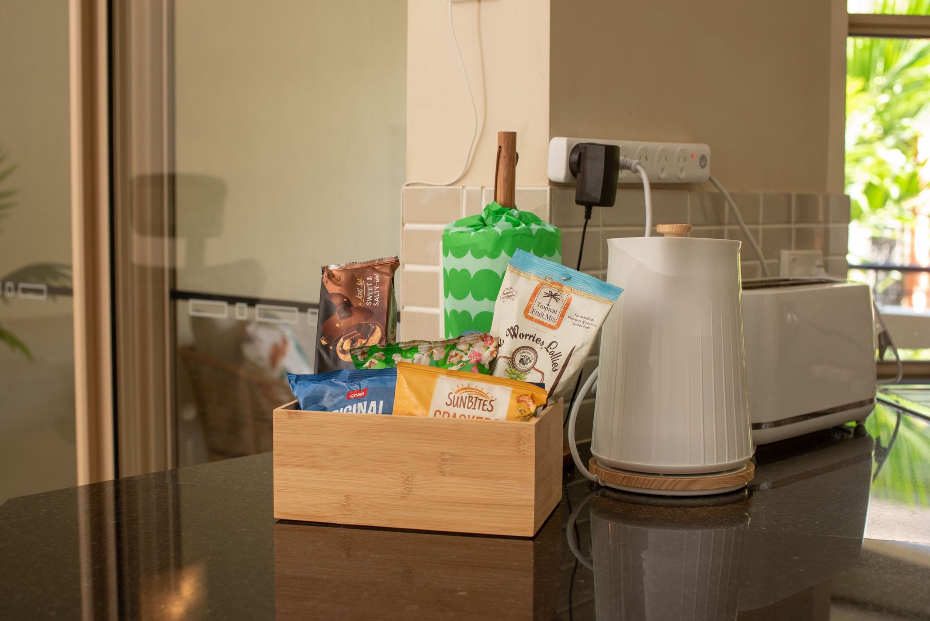 A kitchen counter with a wooden box containing snacks and a white coffee maker.