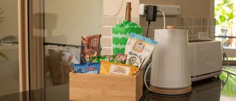 A kitchen counter with a wooden box containing snacks and a white coffee maker.