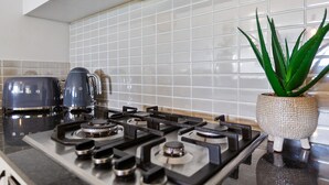 Eine Küche mit einem Gasherd, zwei Wasserkochern und einem Topf mit Aloe Vera.