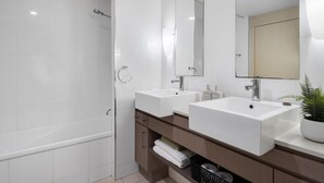 Une salle de bain moderne avec deux lavabos, un grand miroir et une douche à l’italienne.
