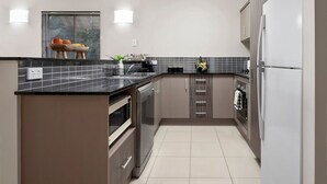 Una cocina moderna con encimera negra, electrodomésticos de acero inoxidable y salpicadero de azulejos.