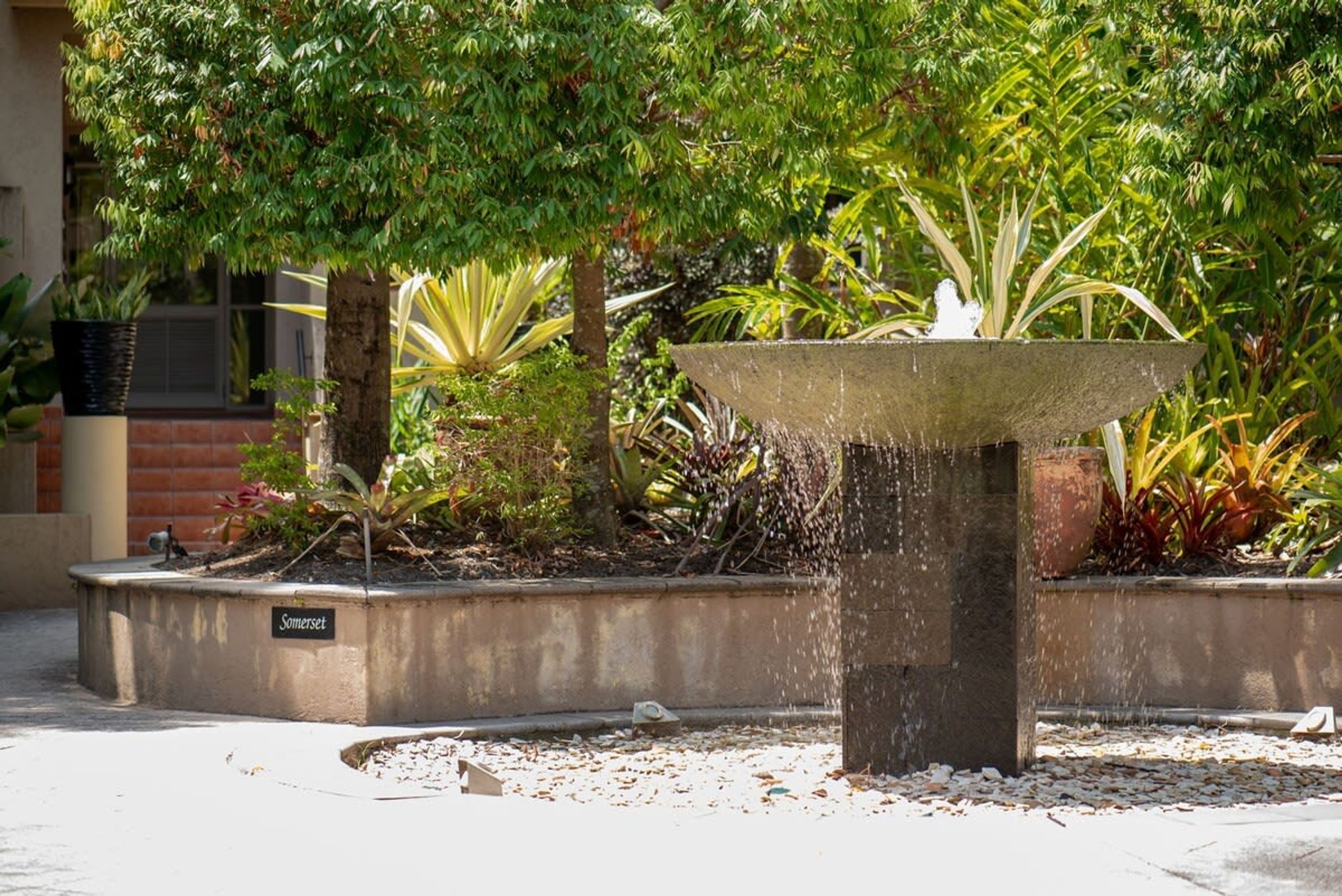 A fountain in a landscaped garden with a sign reading "Somerset."