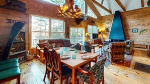 A rustic cabin interior with a dining area, wooden walls, and a large fireplace. - Moose Lane  *Waterfront*ATV/Snowmobile Access* (Greenville)