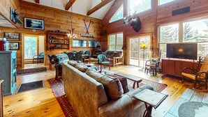 A cozy cabin interior with a wooden interior, a large sofa, dining area, and a mounted moose head. - Moose Lane  *Waterfront*ATV/Snowmobile Access* (Greenville)