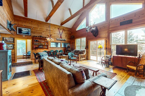 A cozy cabin interior with a wooden interior, a large sofa, dining area, and a mounted moose head.