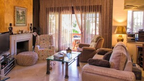 A living room with a fireplace, a television, and a sofa. - Casa La Buganvilla del Chaparral (Marbella)