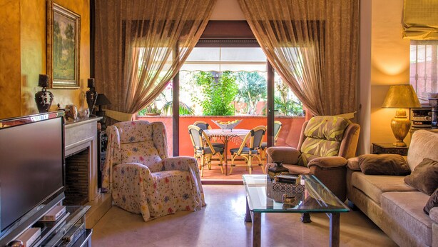 A living room with a fireplace, a television, a sofa, and a dining area with chairs and a table. - Casa La Buganvilla del Chaparral (Marbella)