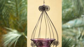 A hanging light fixture with a purple glass shade, surrounded by a metal frame, against a beige wall.