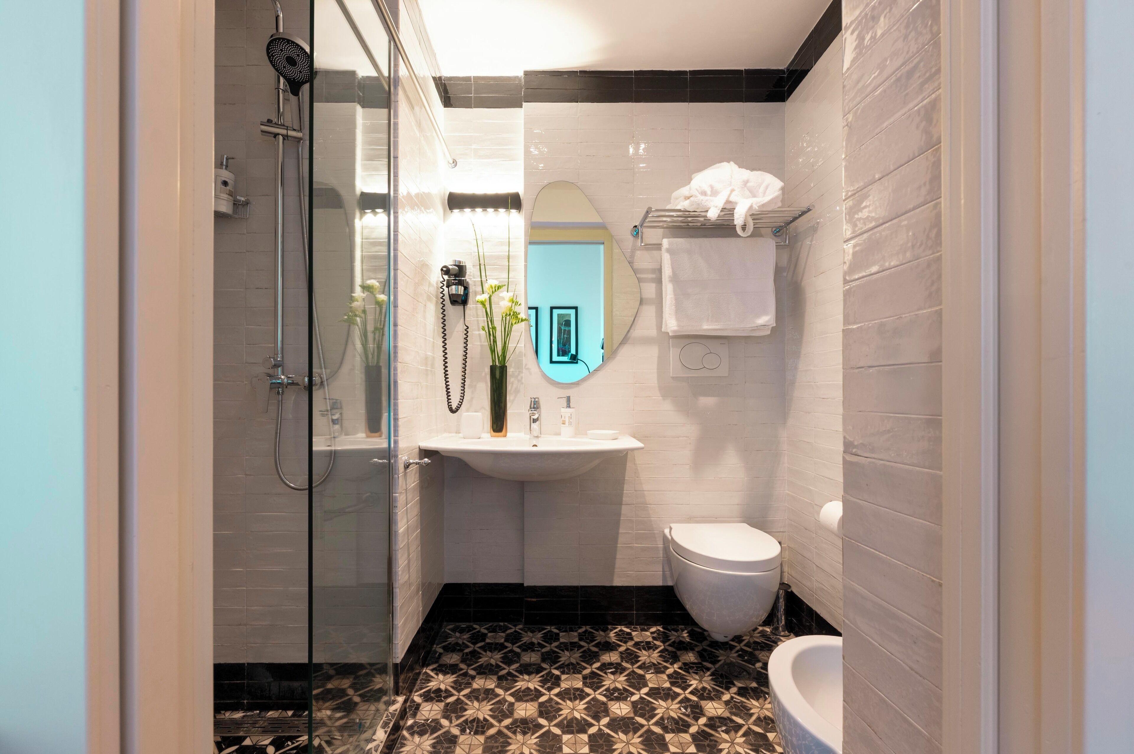 A bathroom with a glass-enclosed shower, a sink with a mirror, and a toilet.