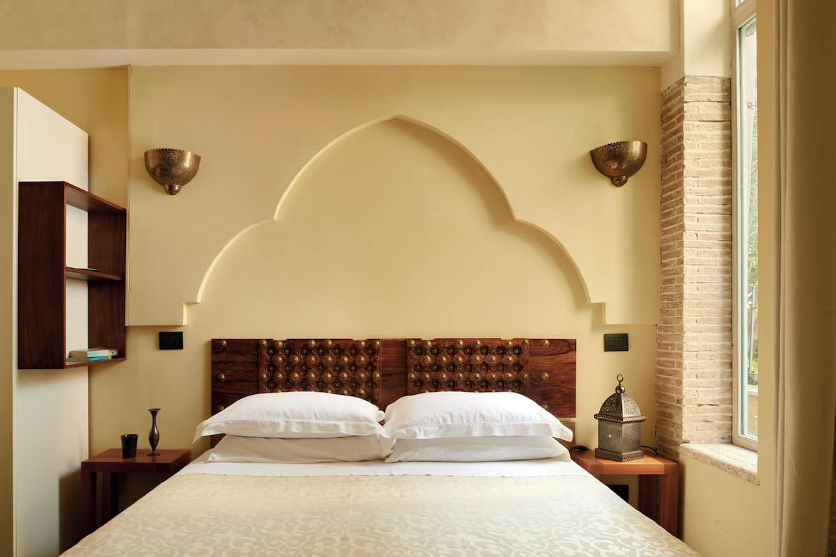 A neatly made bed with a wooden headboard, two bedside tables, and a wall-mounted lamp.