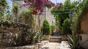 A stone pathway leading to a building with a metal railing and flowering plants.