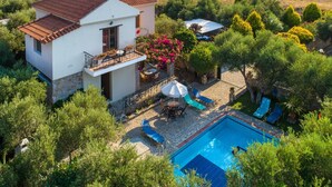 Ein zweistöckiges Haus mit Swimmingpool, umgeben von viel Grün und freiem Blick auf die Landschaft.