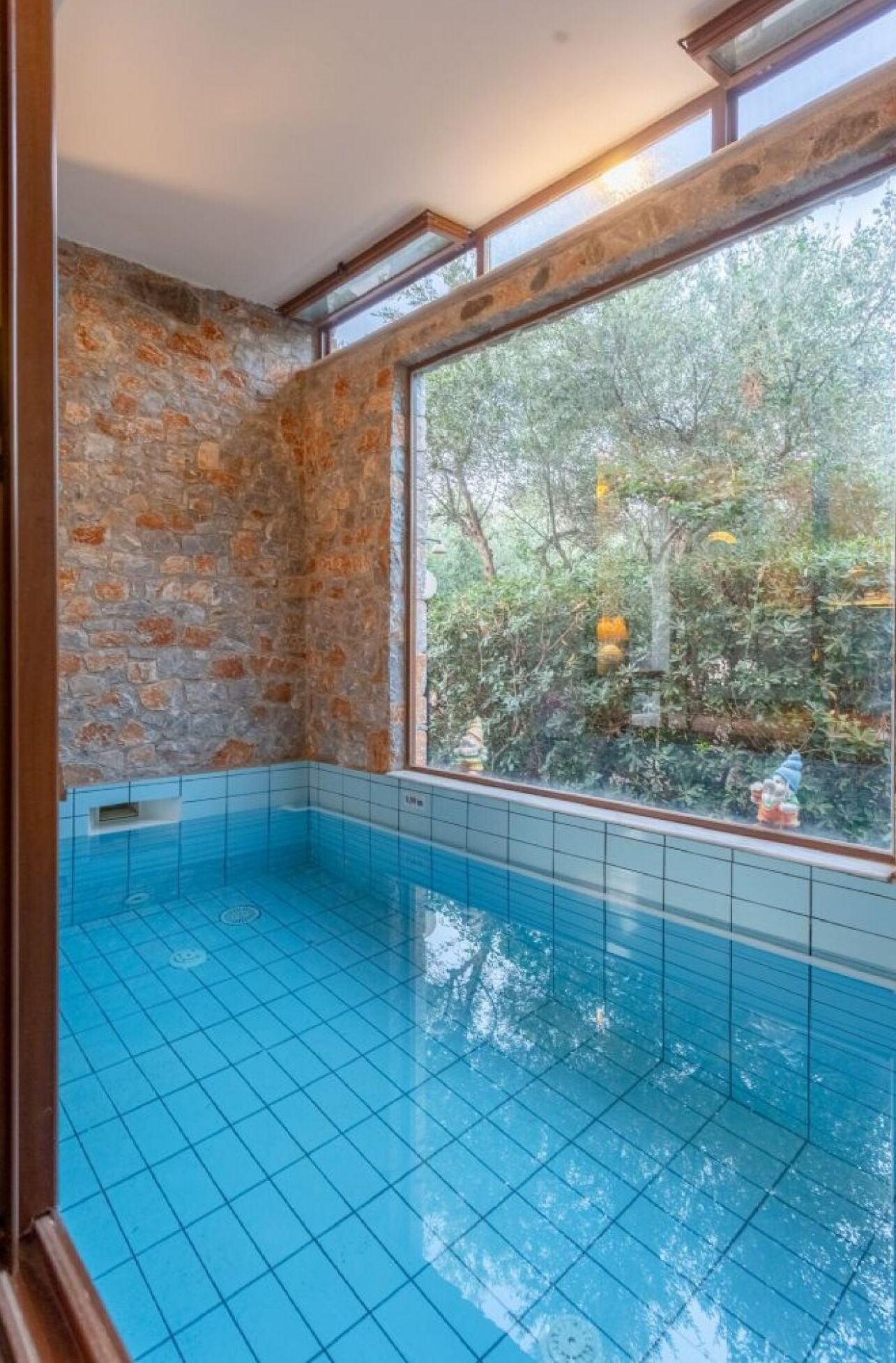 A swimming pool with stone walls and a large window.