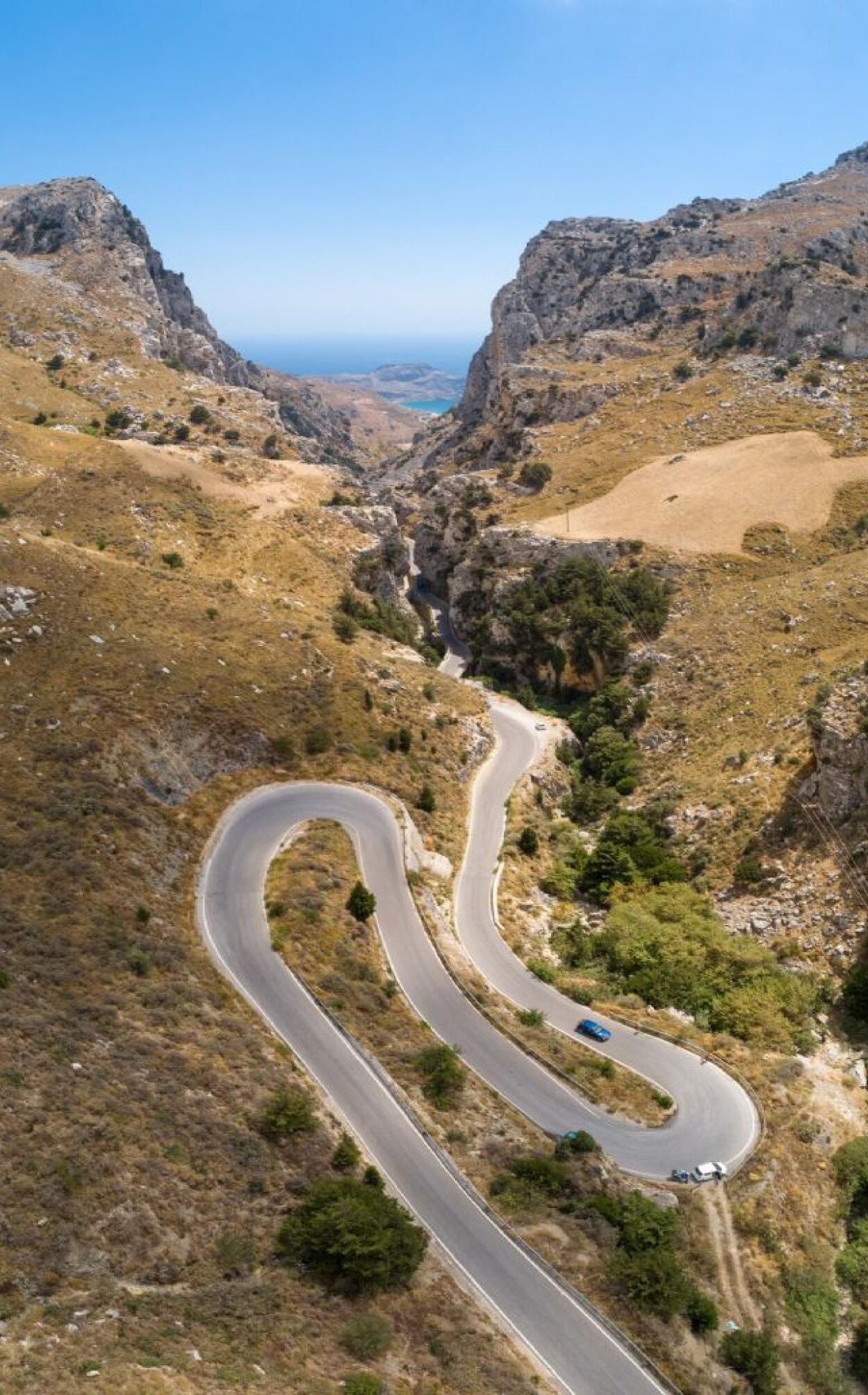 A winding mountain road with a blue car.