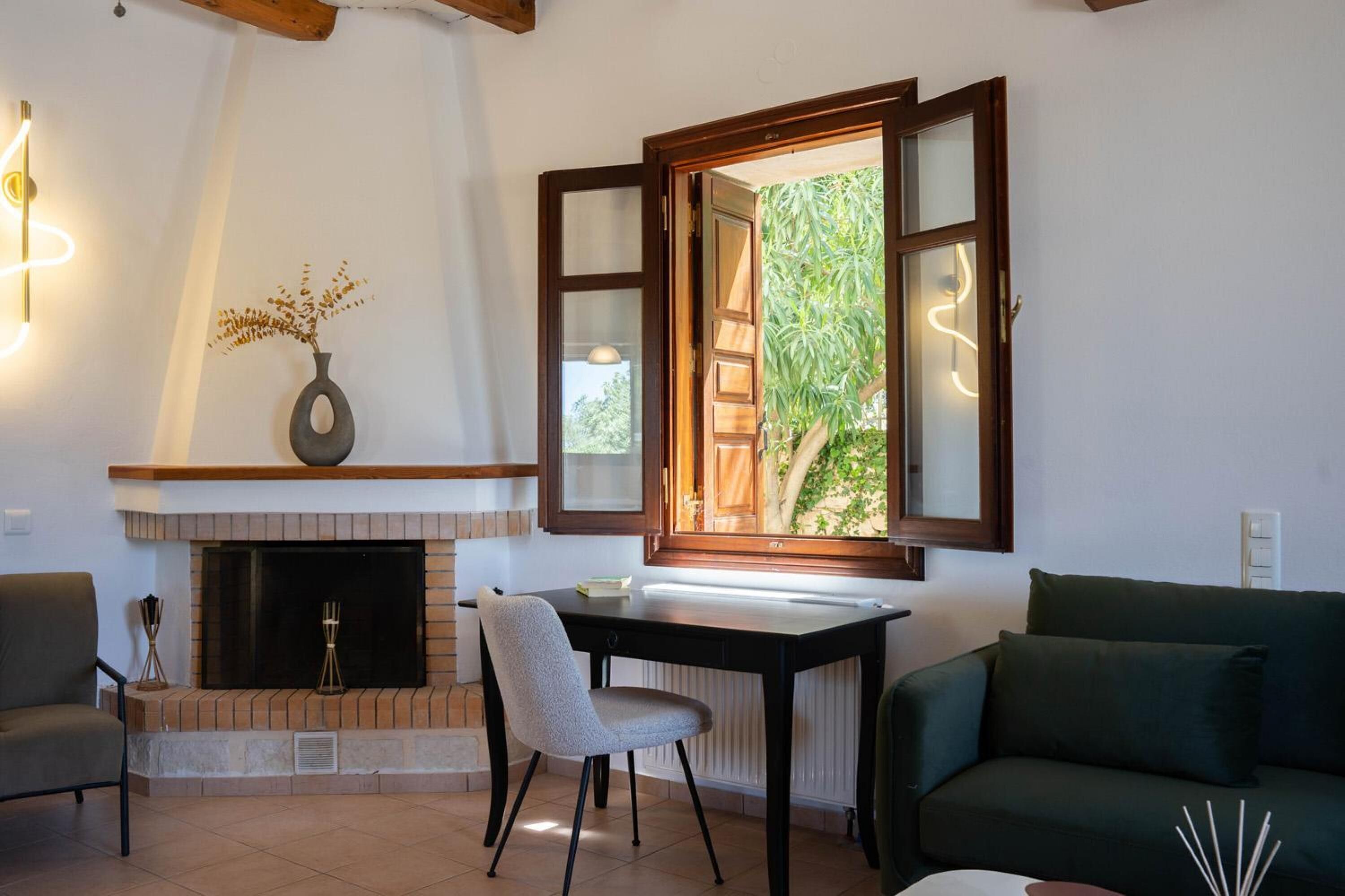 A living room with a fireplace, a table, a chair, and a sofa.