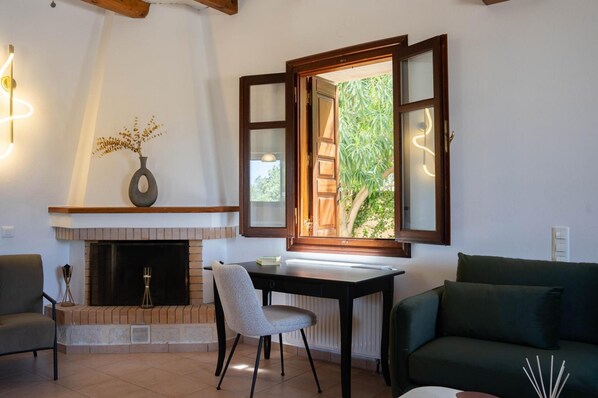 A living room with a fireplace, a table, a chair, and a sofa.