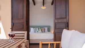 Una habitación acogedora con una cama, una mesa de madera con copas de vino tinto y una silla de madera.