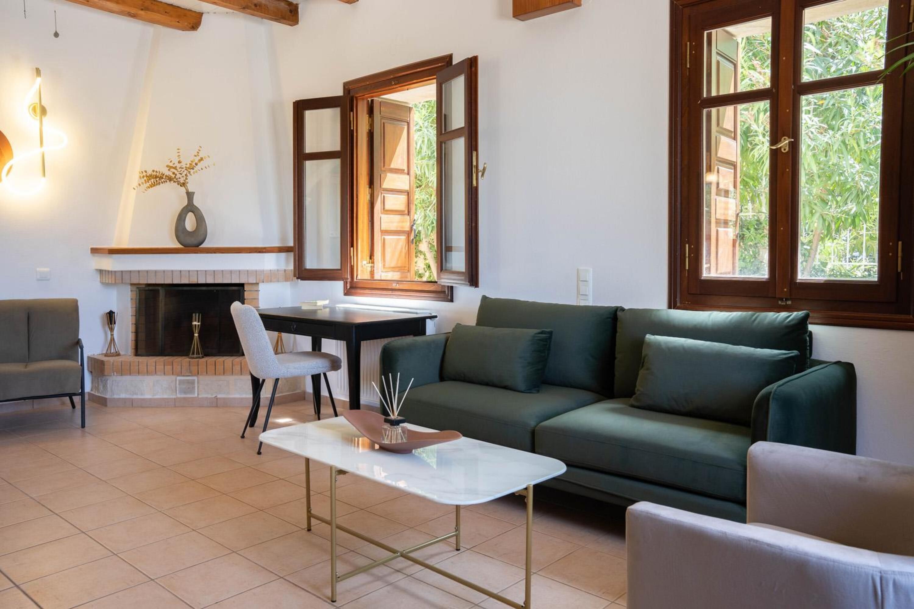 A living room with a green sofa, a white coffee table, a fireplace, and a dining area.