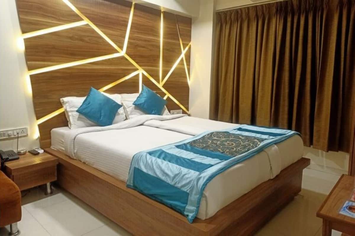 A modern bedroom with a wooden headboard, a bed with blue bedding, and a bedside table with a lamp.