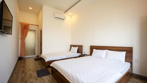 Camera d'albergo con due letti, televisione, condizionatore d'aria e pavimento in legno.