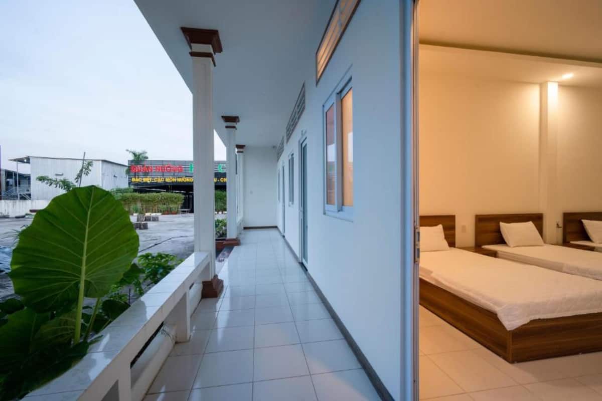 A hotel corridor with a balcony, a bed on the right, and a sign in the background.