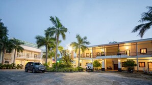 Un hotel a più piani con parcheggio, palme e un ingresso ben illuminato.
