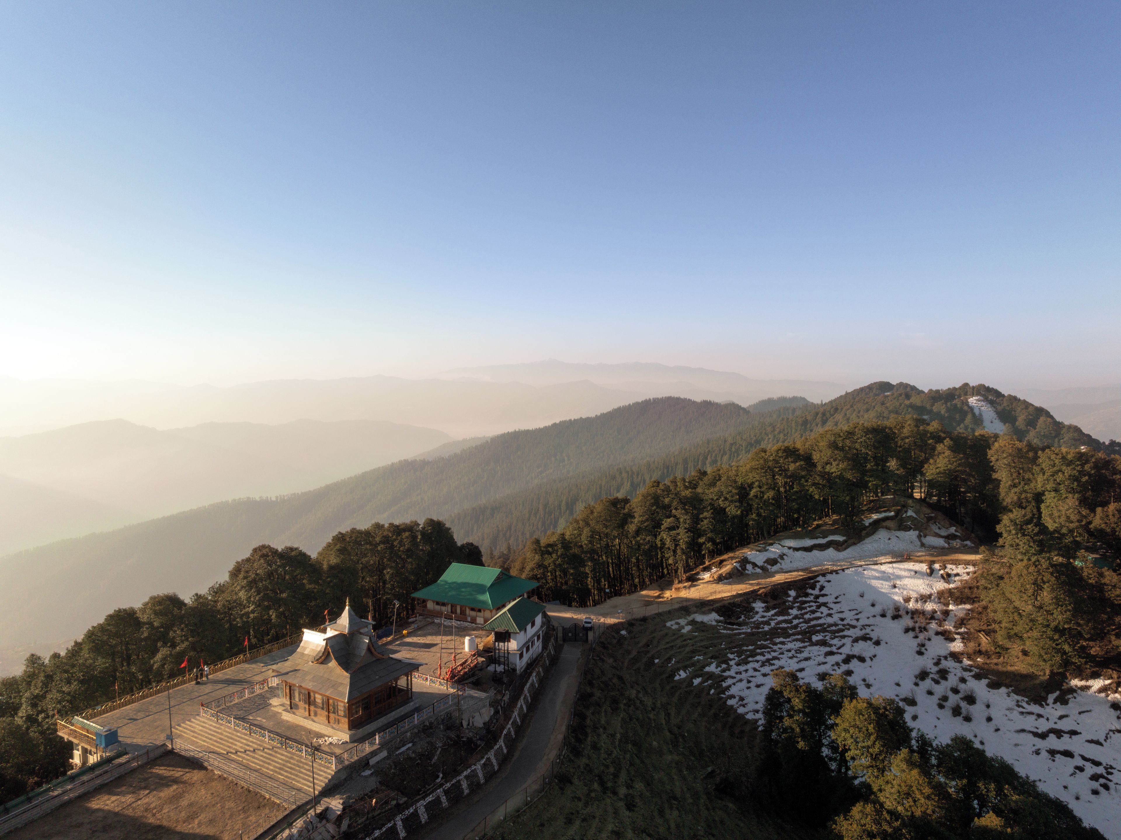 A mountainous landscape with a building featuring a green roof and traditional architecture.