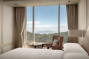 A hotel room with a large window, a bed, a chair, a table, and a lamp. - Greenberry Resort Narkanda, a member of Radisson Individuals Premier (Kumharsain)