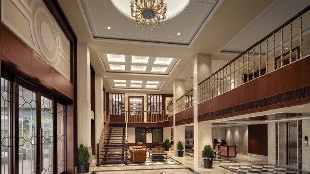 Un'ampia hall con un sontuoso lampadario, un pavimento a scacchi e una scala che conduce a un piano superiore.