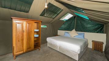 Ein Zeltraum mit Bett, Holzschrank und Dachfenster.