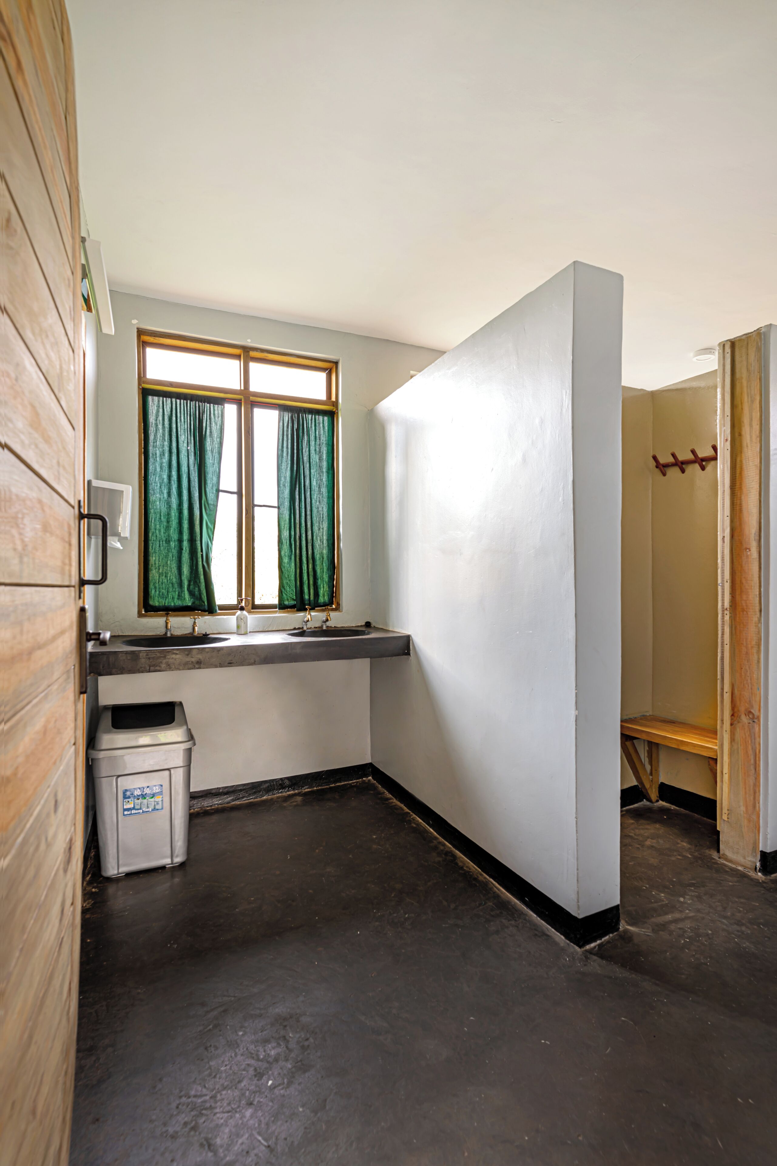 Baño con ventana, lavamanos y cubo de basura.
