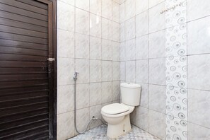 Et lille, rent badeværelse med toilet, brusebad og væg med et cirkulært mønster.