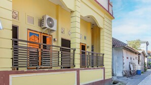 A yellow building with a balcony, a door, and a window. - OYO 94091 Sn Guest House (Denpasar)