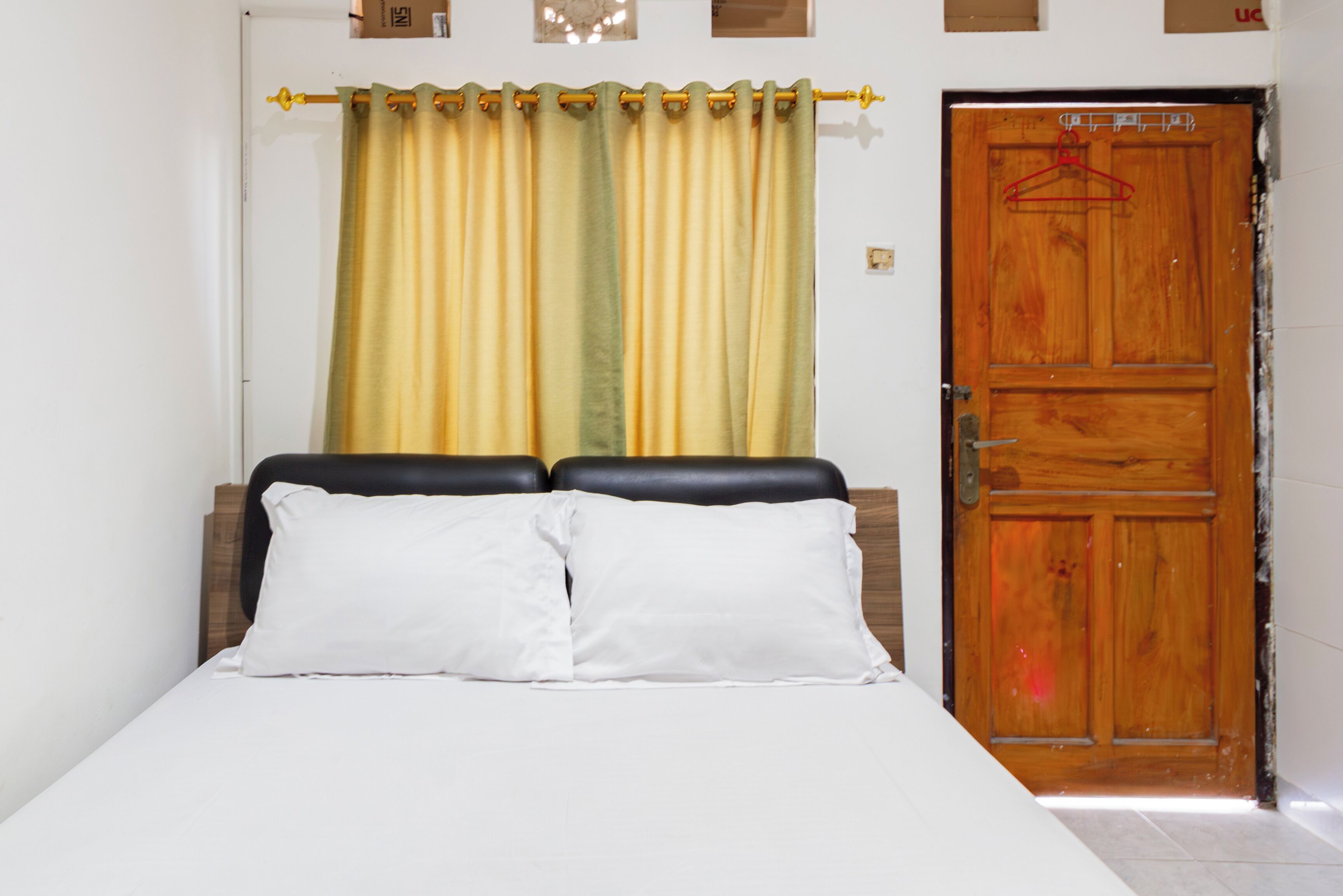 A bedroom with a bed, curtains, and a wooden door.