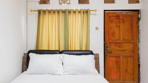 A bedroom with a bed, curtains, and a wooden door. - OYO 94091 Sn Guest House (Denpasar)