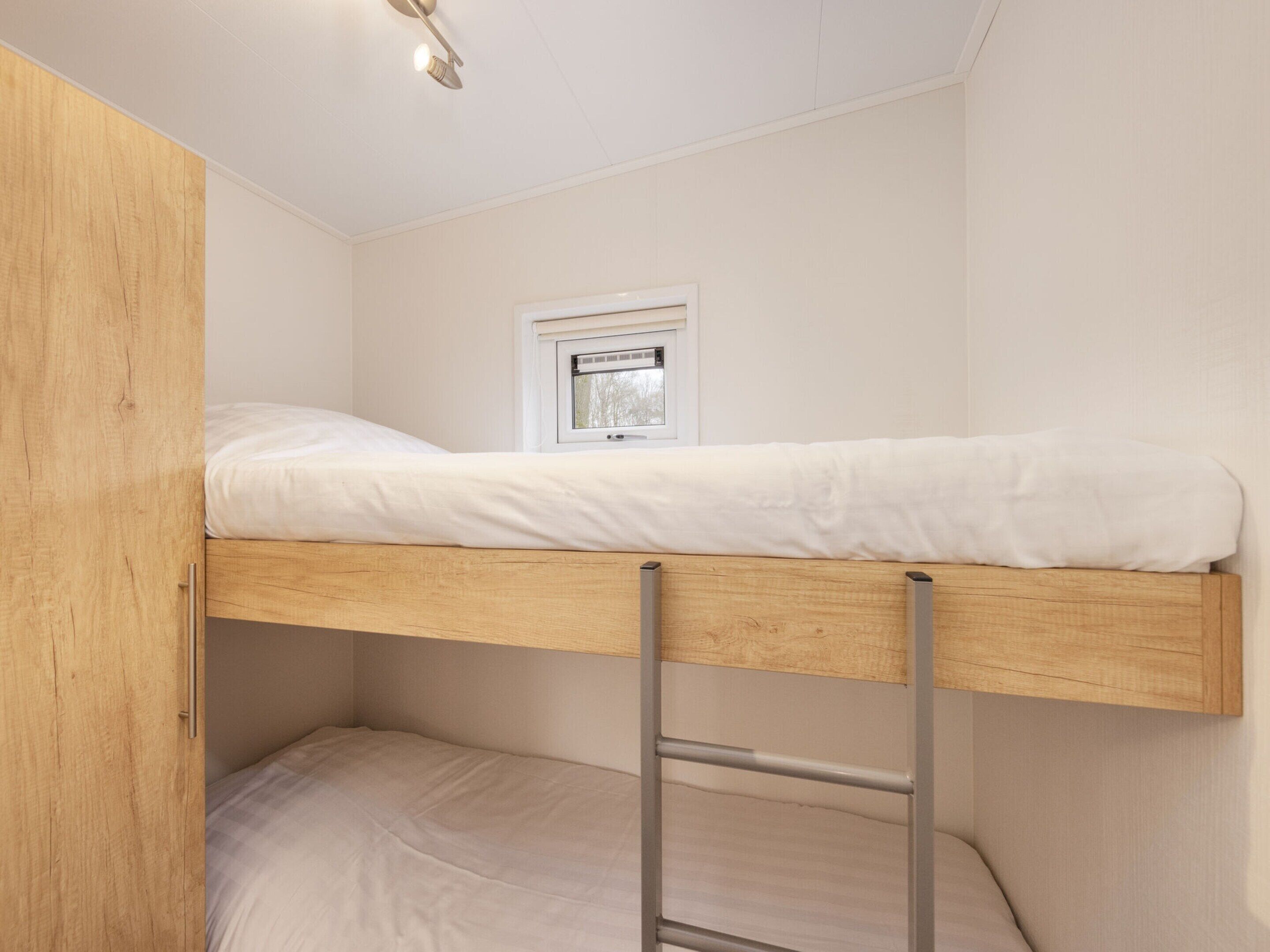 A bunk bed with a window above it.