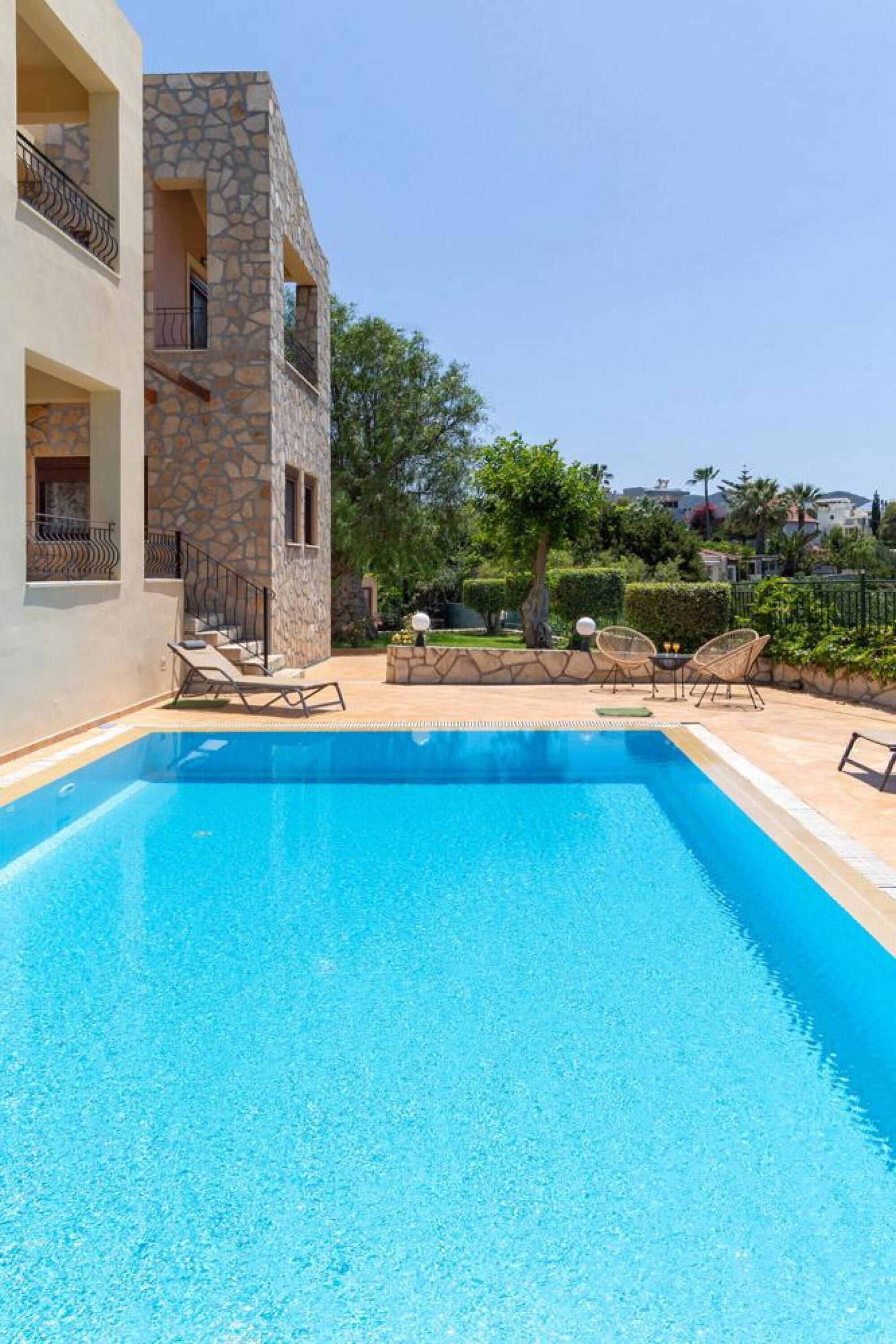 Une piscine avec des chaises longues et, en arrière-plan, un bâtiment en pierre.