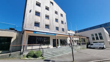 A modern building with a wooden facade, a visible entrance, and a sign for 'SOMMARHOTELL'.