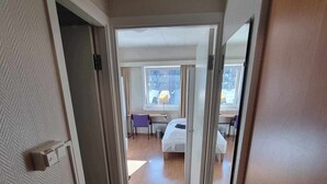 Habitación de hotel con piso de madera, una cama, un escritorio y una silla.