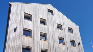Un edificio moderno con fachada de madera y múltiples ventanas. Se puede ver el nombre 'STORD FOLKEHOGSKULEN' sobre la entrada.