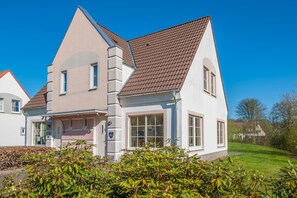 Une maison à deux étages, dotée d’un toit en pente, de grandes fenêtres et d’un numéro bien visible, le « 207 ».