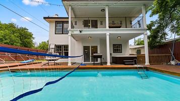 Una casa de dos pisos con piscina, un patio cubierto y una zona de barbacoa.