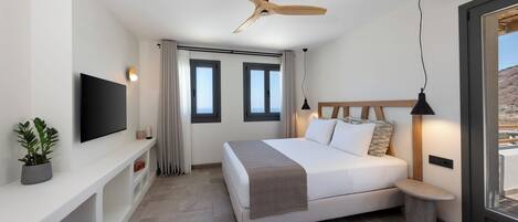 A modern bedroom with a bed, a TV, a ceiling fan, and a window with curtains.