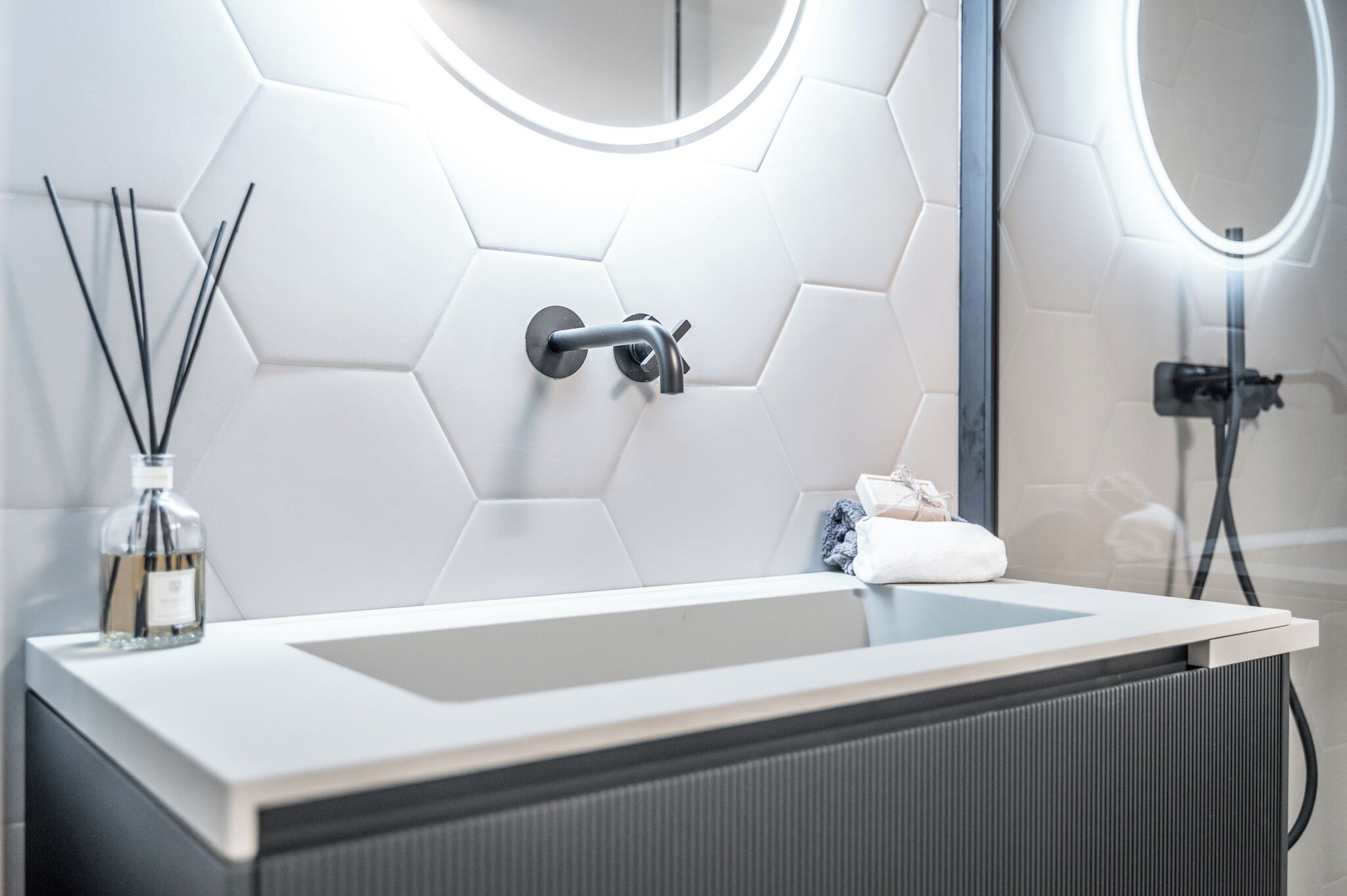 Un bagno con un lavandino bianco, uno specchio e un motivo a esagoni sulla parete.