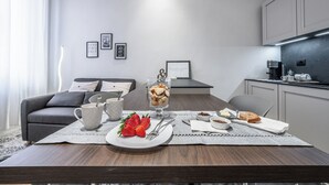 En moderne stue med et spisebord dækket til morgenmad, med glasdessert, jordbær og brød.