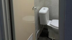 A small, compact bathroom with a toilet, a shower stall, and a towel rack. - Hotel O Fgh Residence 1 (Bekasi)