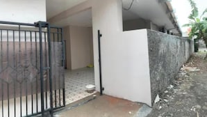 A gated entrance with a metal gate, a concrete pathway, and a white wall. - Hotel O Fgh Residence 1 (Bekasi)