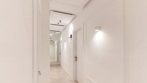 A corridor with white walls and doors, leading to a mirrored area. - Diff'rent Souls Rooms (Sorrento)